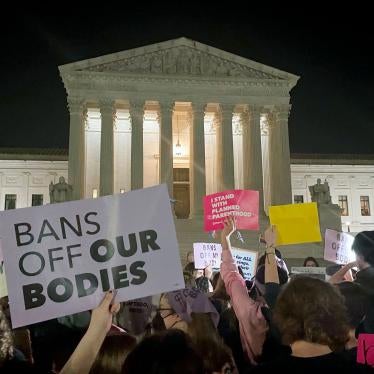 People protest holding signs outside of the US Supreme Court at night