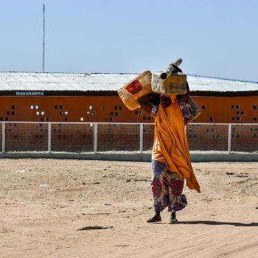 A woman carries belongings over her head