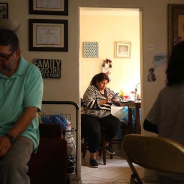 Marisol Coronado, center, prepares for a zoom call, while her husband and son spend time in the living room of their apartment in Huntington Park on April 19, 2024.