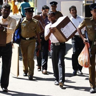 Polling officers carrying ballot boxes walk with a police officer as they prepare to go to their polling centers ahead of presidential election in Colombo on January 7, 2015.