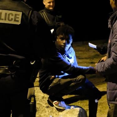 Police check identity documents after halting a distribution of food, water, and clothing in an industrial area of Calais shortly after midnight on June 30, 2017.