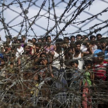 Rohingya refugees gather behind a barbed-wire fence in the “no-man’s land” border zone between Myanmar and Bangladesh, April 25, 2018.