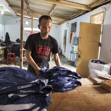 Man working in a clothing factory in Indonesia, stitching buttons 