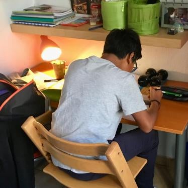 A boy sitting at his desk in his room doing homework