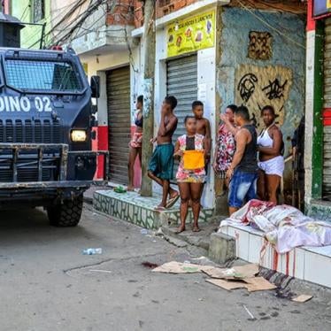 A military police armored vehicle passes by a person killed by police on April 7, 2016 in the Jacarezinho favela. Military police killed tow other people during the same raid. 
