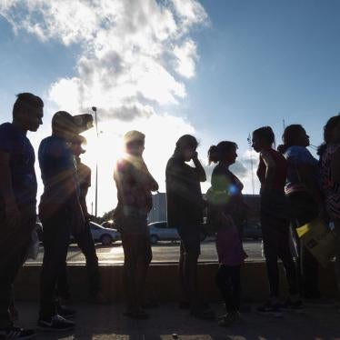 Migrants seeking asylum wait in line with their case paperwork on October 5, 2019