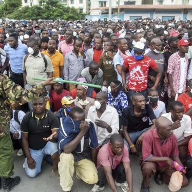 Kenyan police hold back ferry passengers causing a crowd to form outside the ferry in Mombasa, Kenya on Friday, March 27, 2020. 