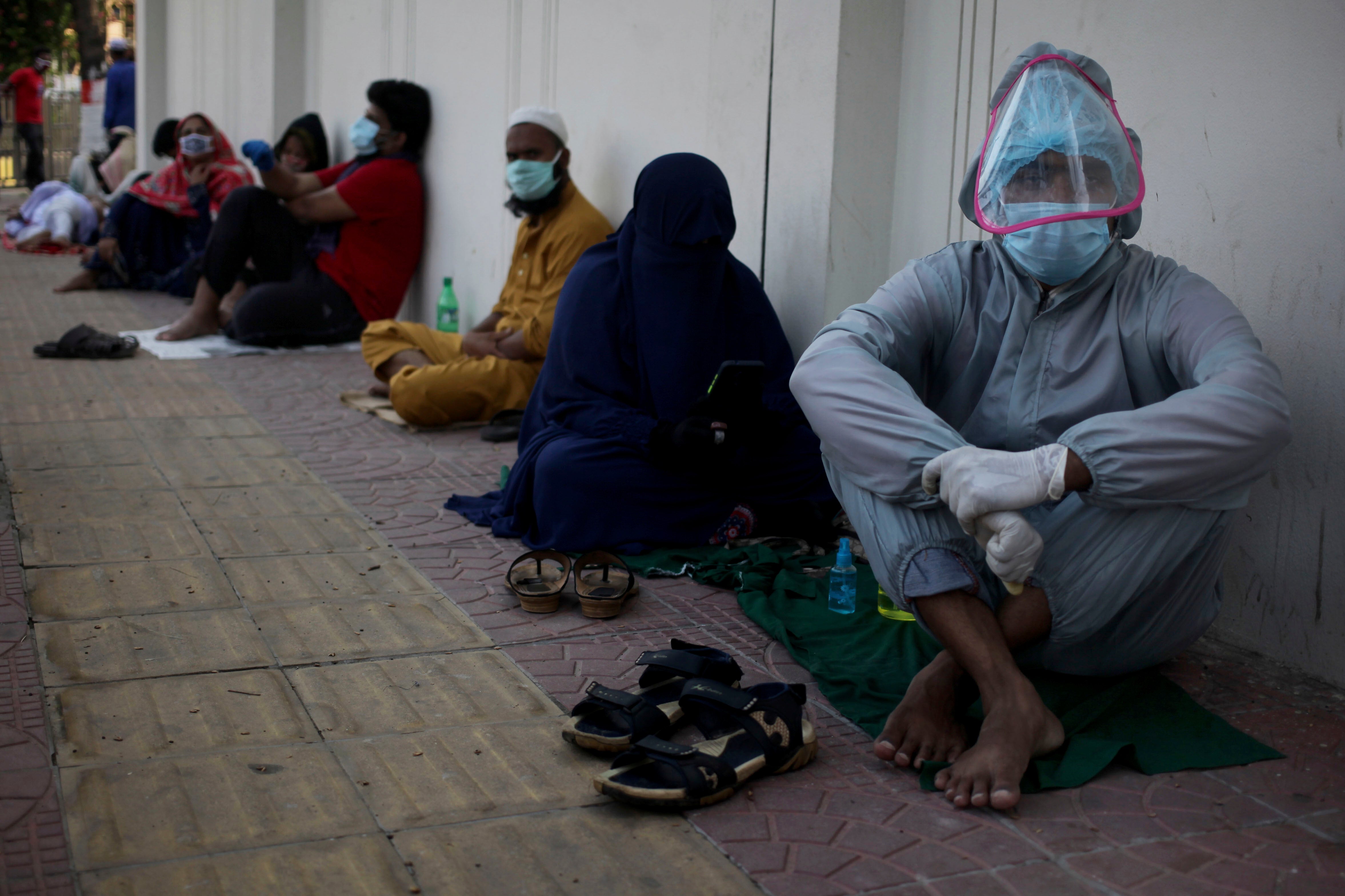 Patients sit on the ground as they wait in queue outside of a hospital for Covid-19 test in Dhaka, Bangladesh on May 16, 2020. 