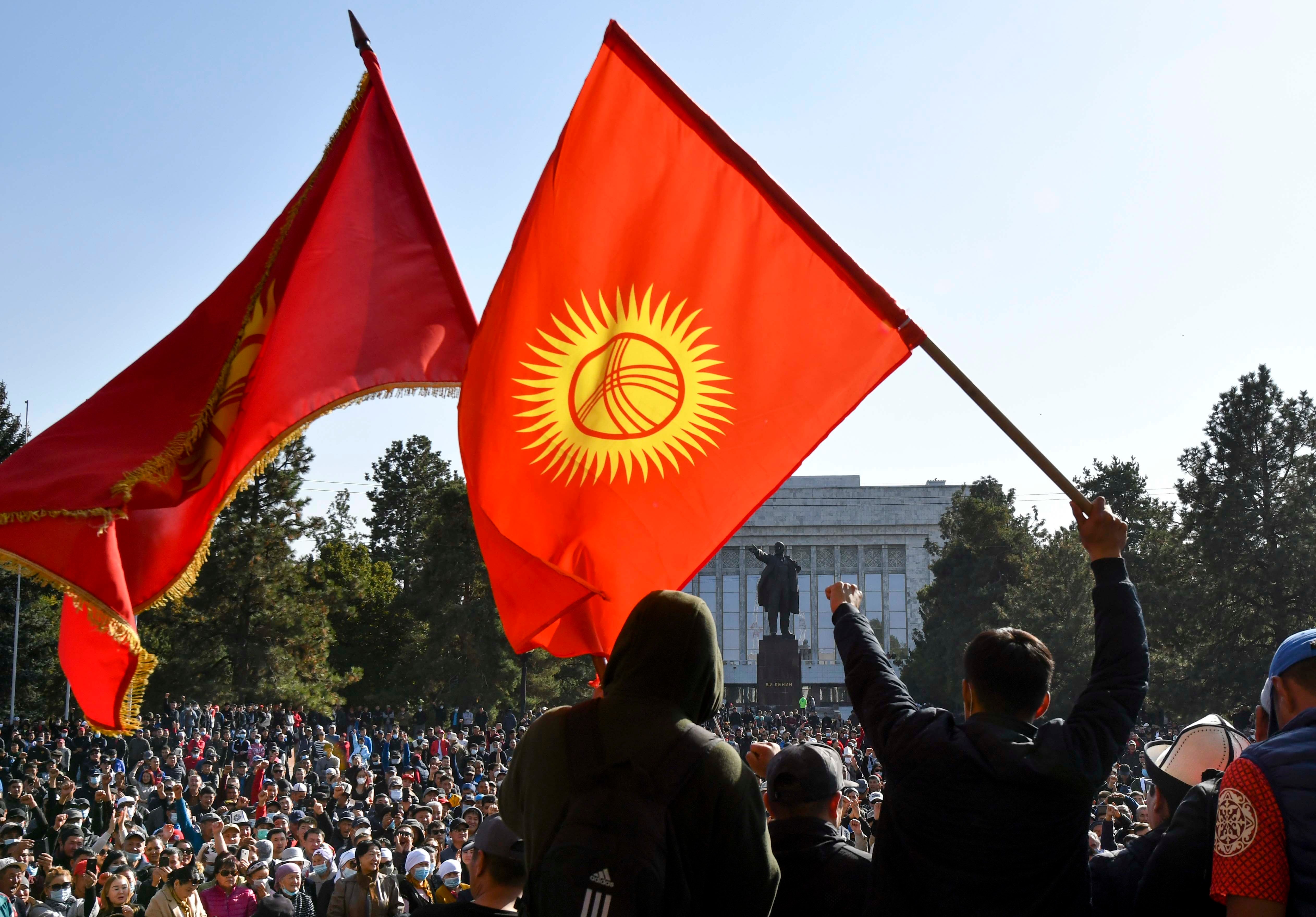 Протестующие размахивают национальными флагами, ожидая выступления премьер-министра Кыргызстана Садыра Жапарова перед зданием правительства в Бишкеке, Кыргызстан, 14 октября 2020 г.