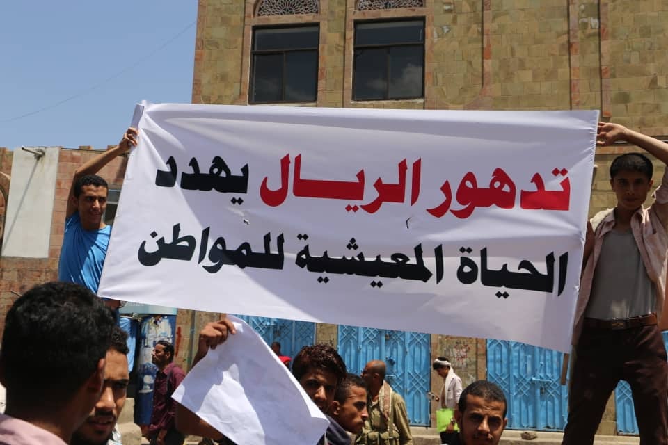 متظاهرون يحملون لافتة تقول: "تدهور الريال يهدد الحياة المعيشية للمواطن"، تعز، اليمن، ديسمبر/كانون الأول 2018. 
