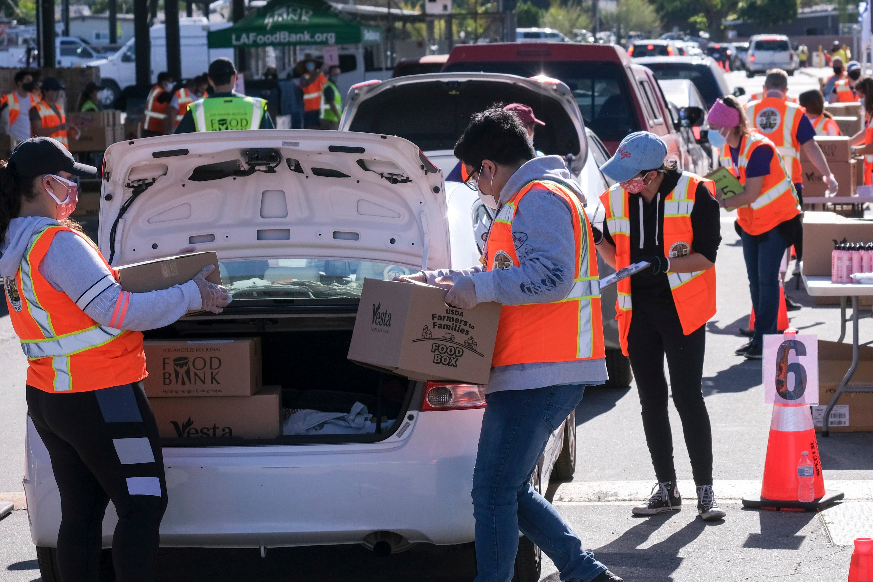 Voluntarios ponen alimentos en el maletero de automóviles durante la campaña de distribución vehicular de alimentos “Let’s Feed LA County” organizada por Los Angeles Regional Food Bank y la Oficina de la Supervisora Hilda Solís el 23 de febrero de 2021, en La Puente, California. 