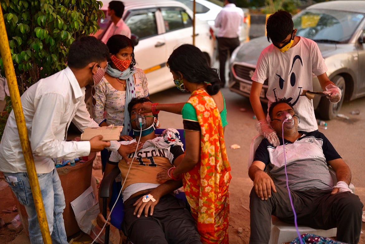Deux hommes souffrant de troubles respiratoires probablement liés à la propagation du coronavirus reçoivent de l’oxygène par le biais de masques médicaux, près de l’entrée d’un gurdwara (lieu de culte de la communauté sikh), à Delhi, en Inde, en avril 2021. 