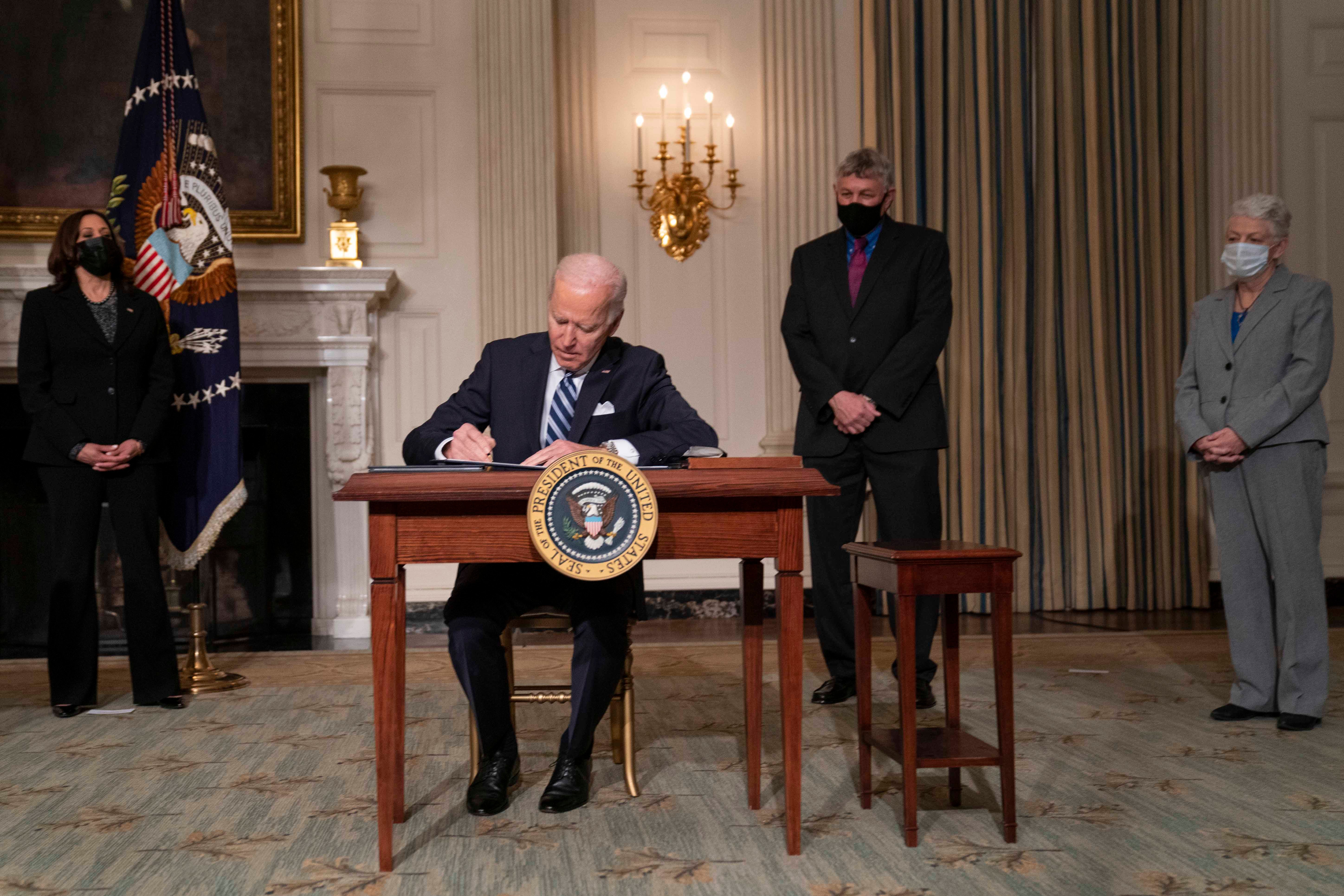 الرئيس الأمريكي جو بايدن محاطا بمعاونيه يوقع سلسلة أوامر تنفيذية للتصدي لأزمة المناخ في 27 يناير/كانون الثاني 2021 في واشنطن. 