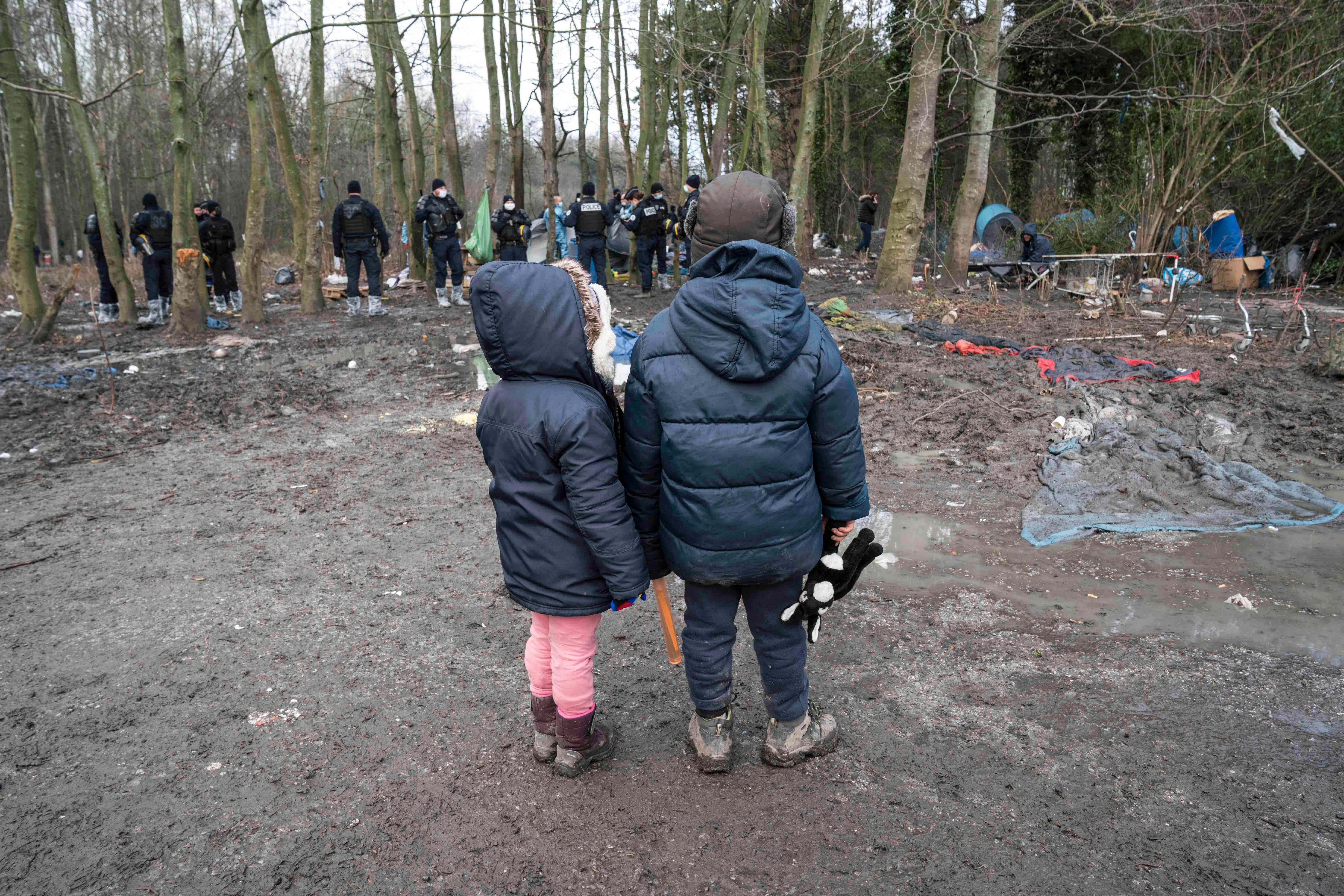 Dos niños observan cómo la policía confisca su tienda de campaña durante el desalojo de un campamento de inmigrantes en Grande-Synthe, en el norte de Francia, el 21 de enero de 2021.
