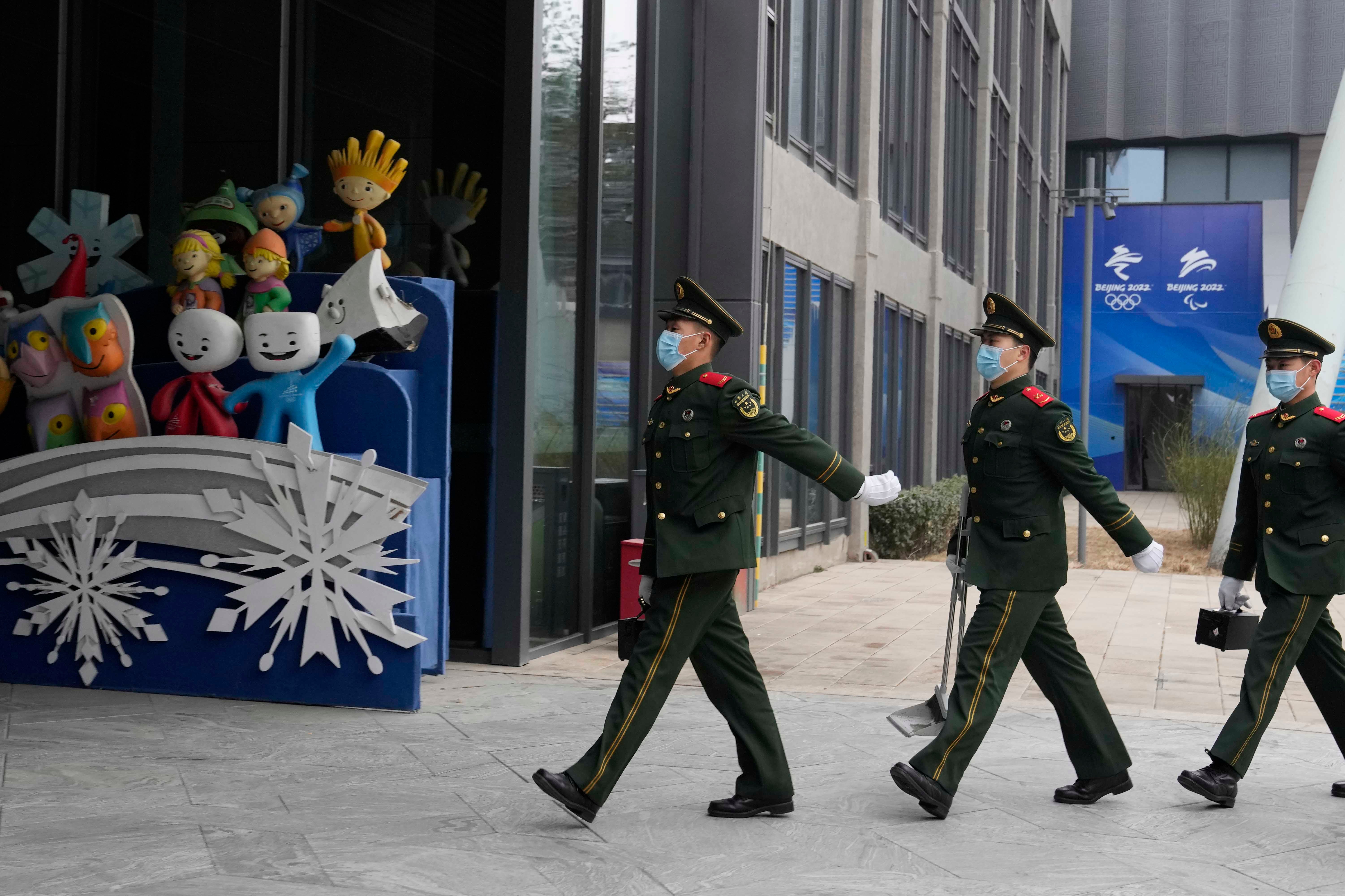 عناصر من الشرطة شبه العسكرية الصينية يسيرون بجانب دميات رسمية للألعاب الأولمبية الشتوية في منتزه شوغانغ في بكين، الصين، 21 يناير/كانون الثاني 2022. © 2022 أسوشيتد برس/نغ هان غوان 