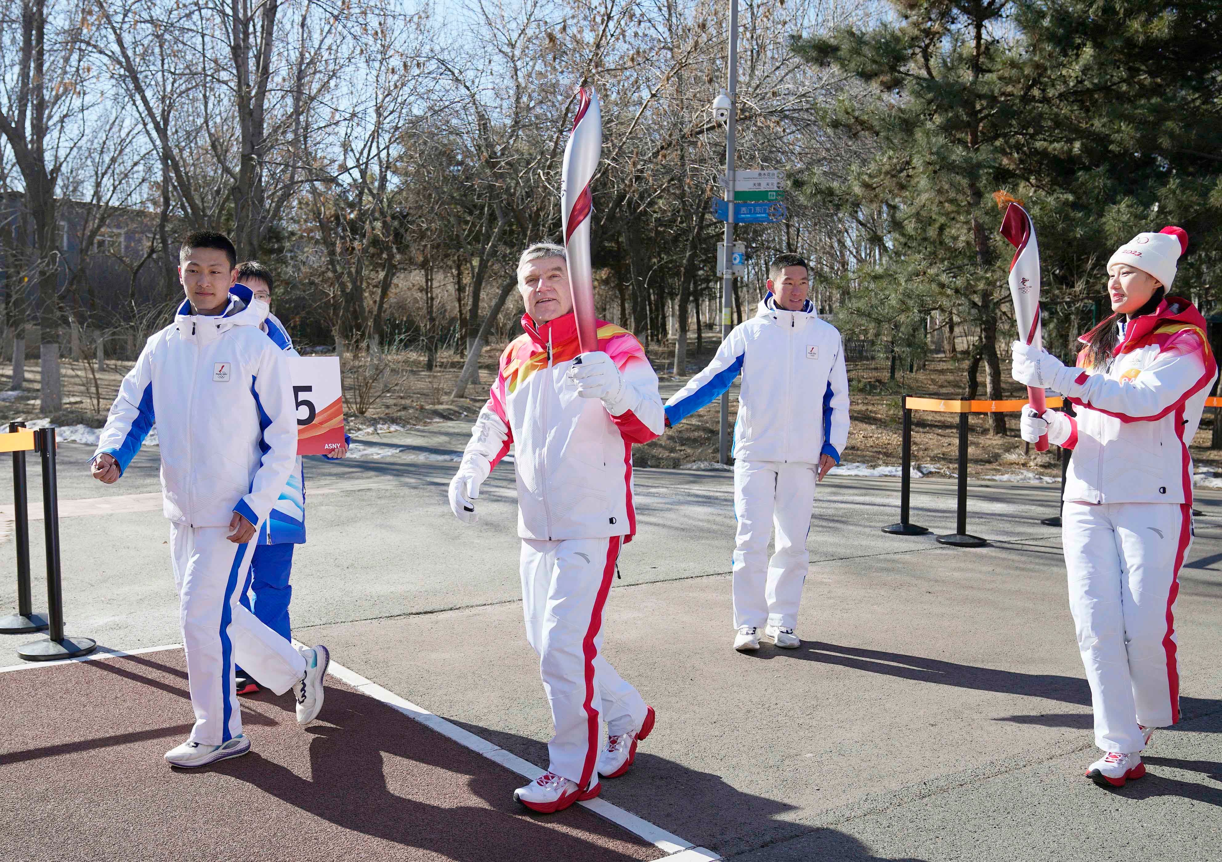 Le président du Comité international olympique Thomas Bach (en tenue blanche-rouge) participait à l’ultime phase du relais de la Flamme olympique à Pékin le 4 février 2022, peu avant la cérémonie d'ouverture des JO d’hiver 2022 accueillis par la Chine.