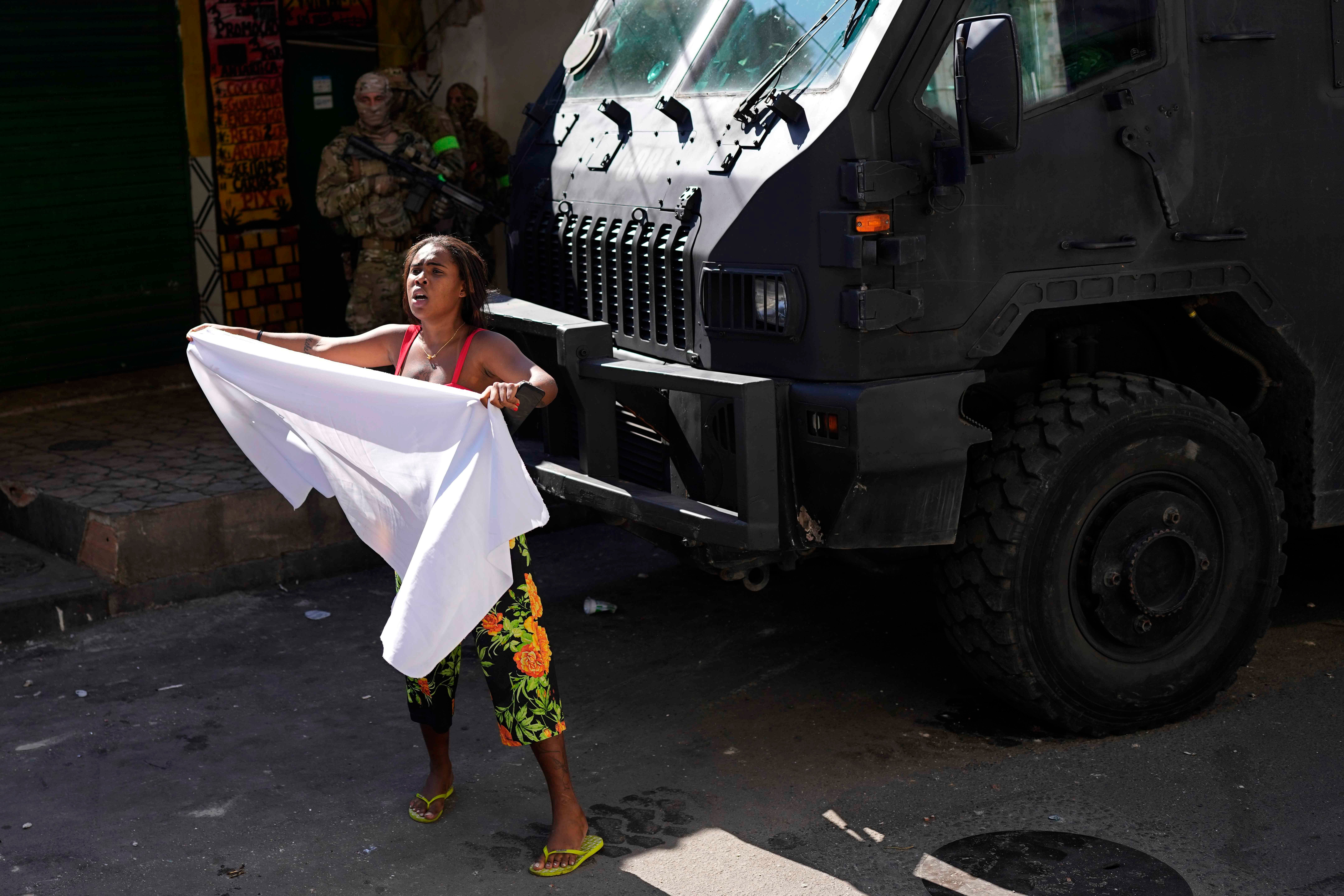 Uma moradora acena com lençol branco pedindo paz após uma operação policial que resultou em várias mortes, no Complexo do Alemão, no Rio de Janeiro, Brasil, 21 de julho de 2022. 