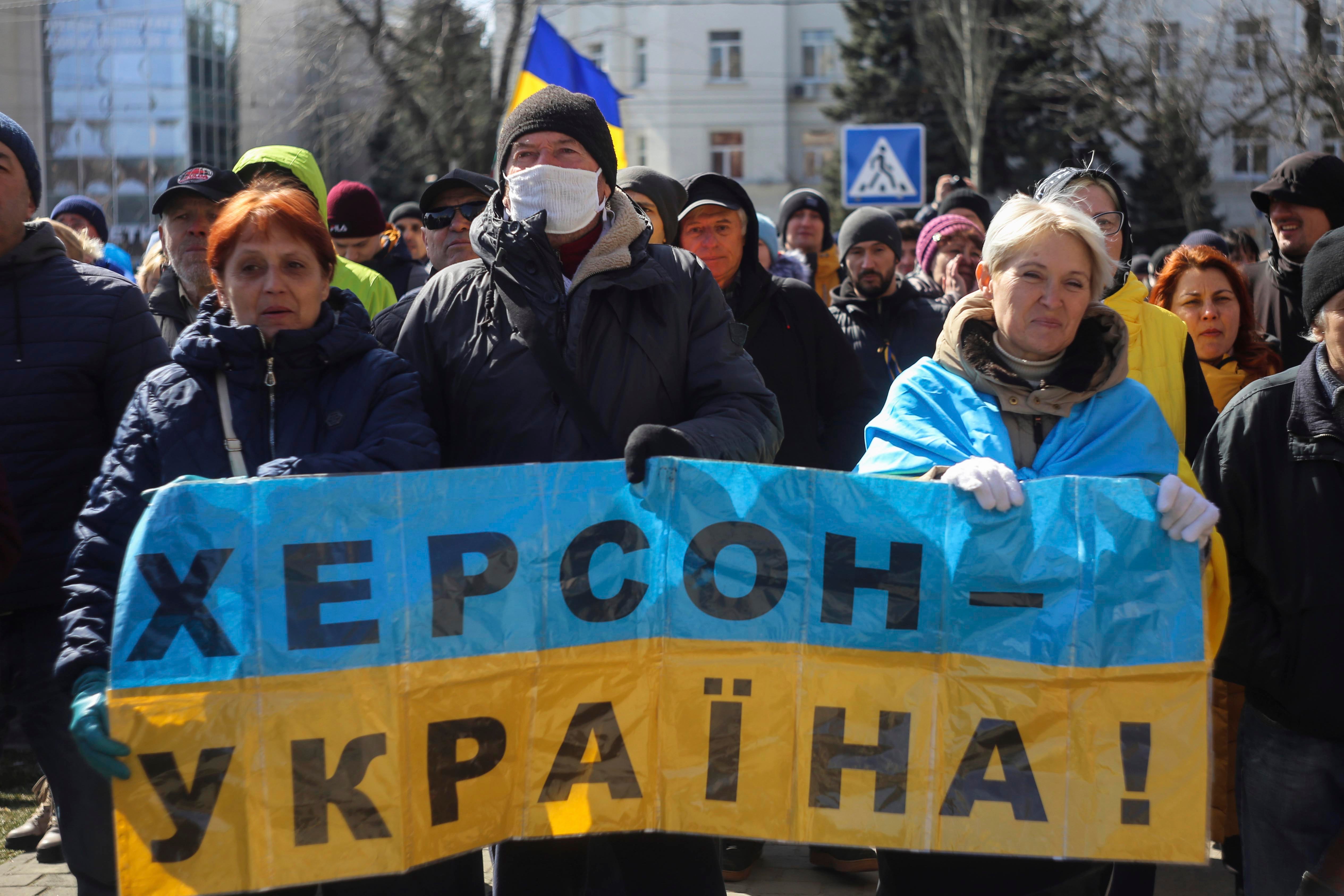Des manifestants tiennent un drapeau ukrainien avec une pancarte qui affirme : « Kherson, c’est l’Ukraine », lors d’un rassemblement contre l’occupation russe à Kherson, en Ukraine, dimanche 20 mars 2022. 