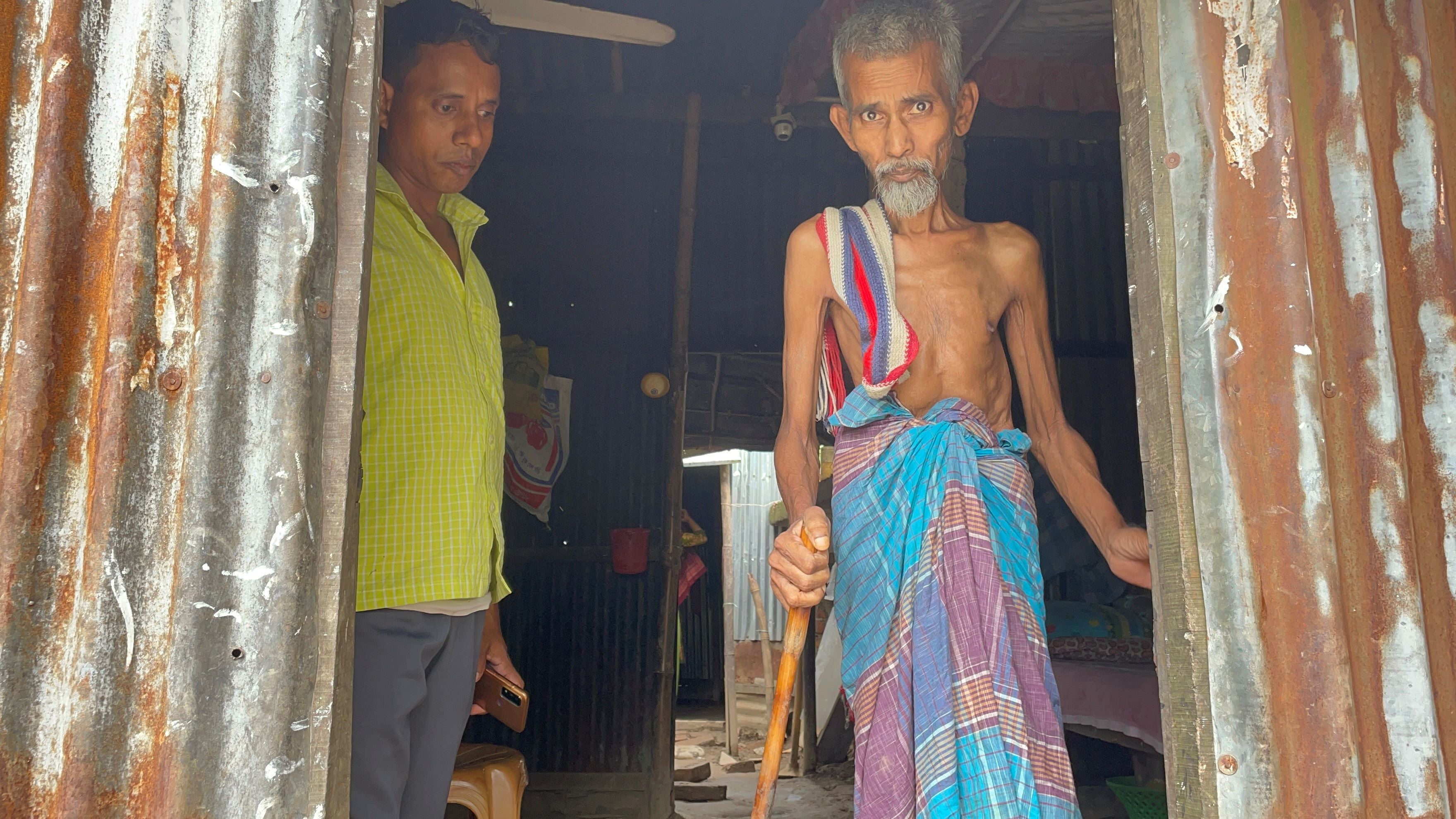 A older man stands in a doorway next to his son