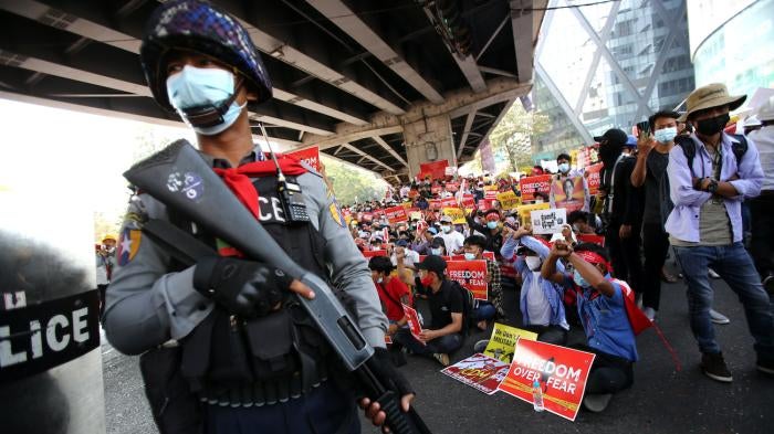 A police officer stands in front of anti-coup protesters in Yangon, Myanmar, February 19, 2021.