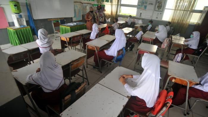 Schoolgirls sit at desks in a classroom