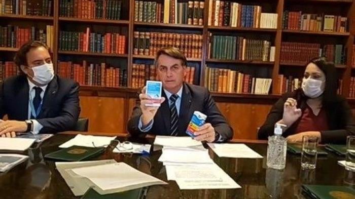 Brazil's President Jair Bolsonaro holds a drug he recommended to treat Covid-19 during a Facebook live event in April 2020. That drug has no proven effect against the virus.