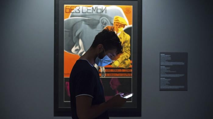 A young man wearing a face mask checks his mobile phone at the State Russian Museum, Saint Petersburg, May 26, 2020.