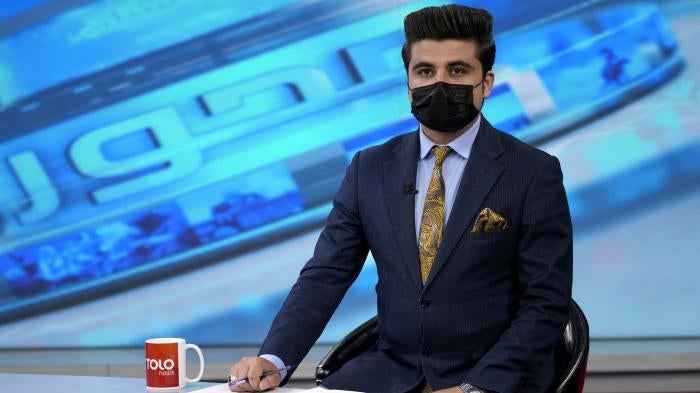 A tv anchor wears a face mask on the air