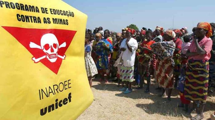 Villagers stand in front of a Unicef banner warning of landmines outside Caala, Angola