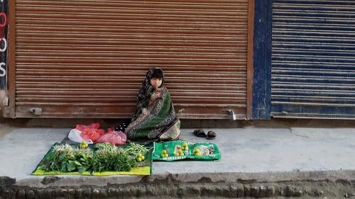 A child sits on the sidewalk in front of a display of goods to sell