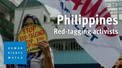 A woman holds up a sign protesting red-tagging in the Philippines 