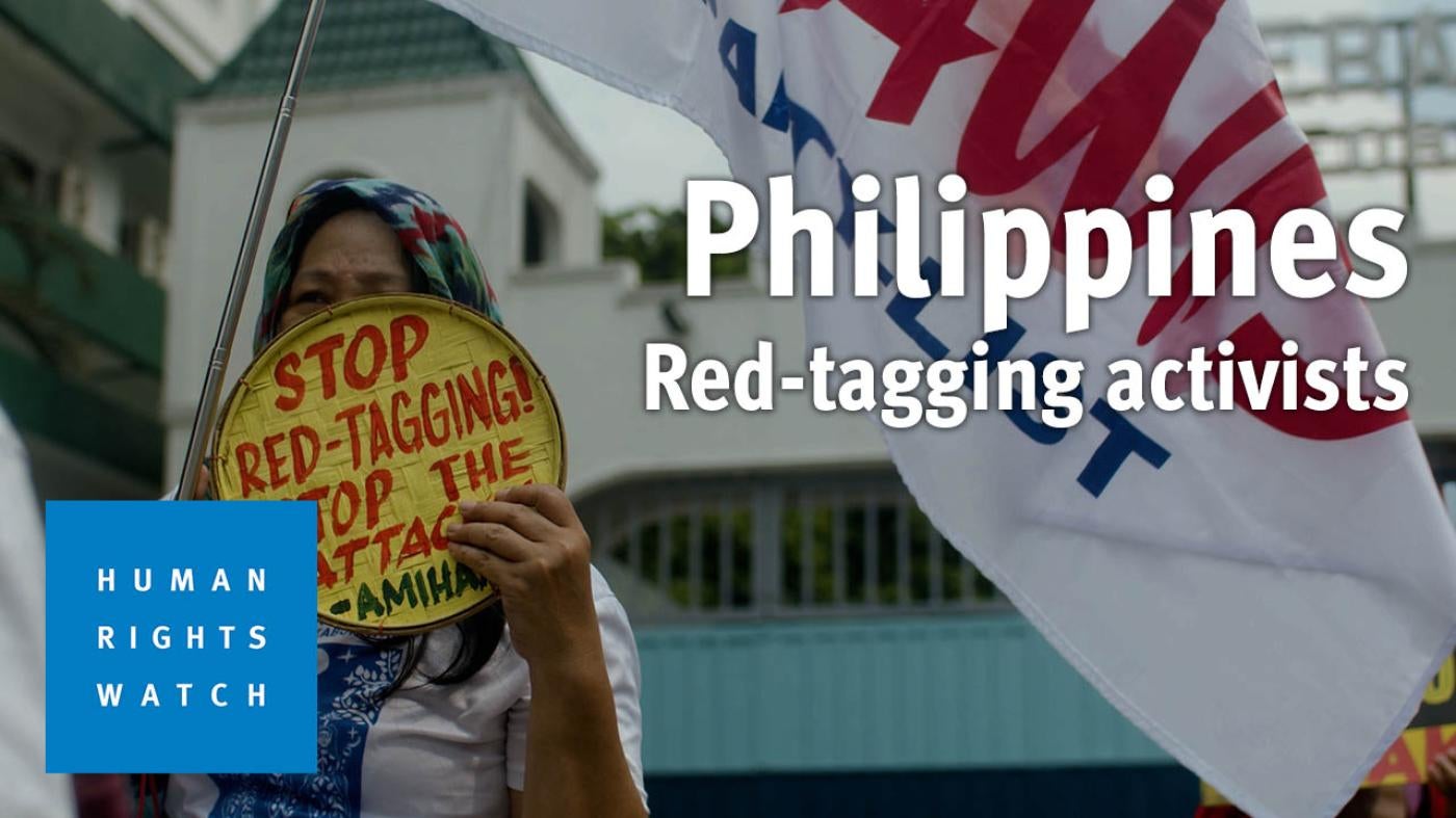A woman holds up a sign protesting red-tagging in the Philippines 