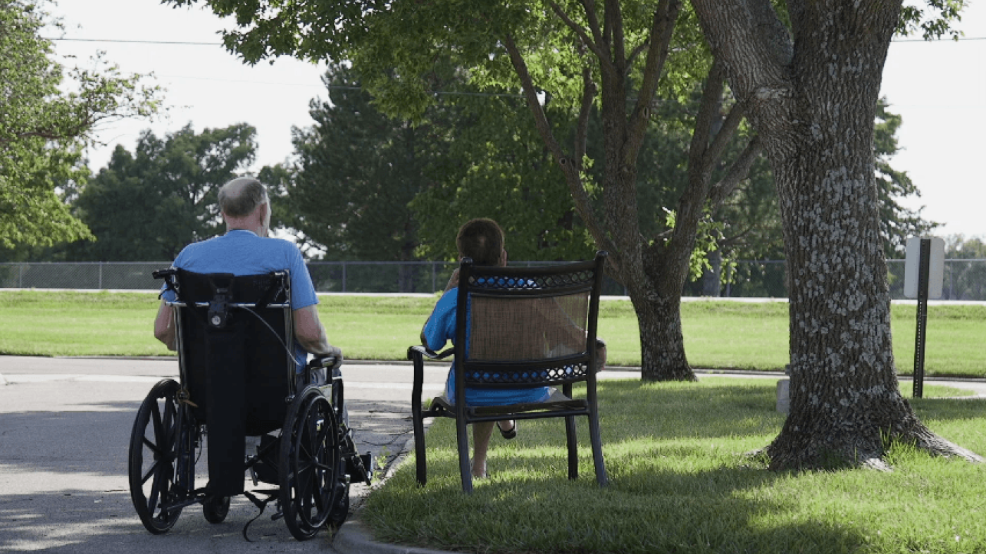 Photo of people sitting outside a nursing home. 