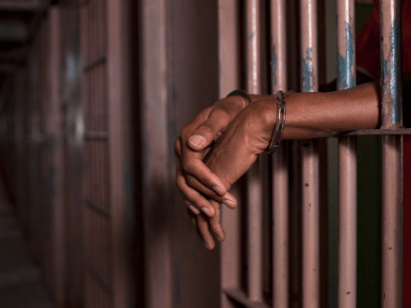 hands sticking through bars of a jail 