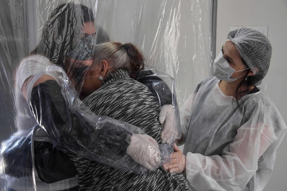 Женщина обнимает свою 85-летнюю мать через прозрачный пластиковый занавес в доме престарелых в Сан-Паулу (Бразилия) в июне 2020 года.