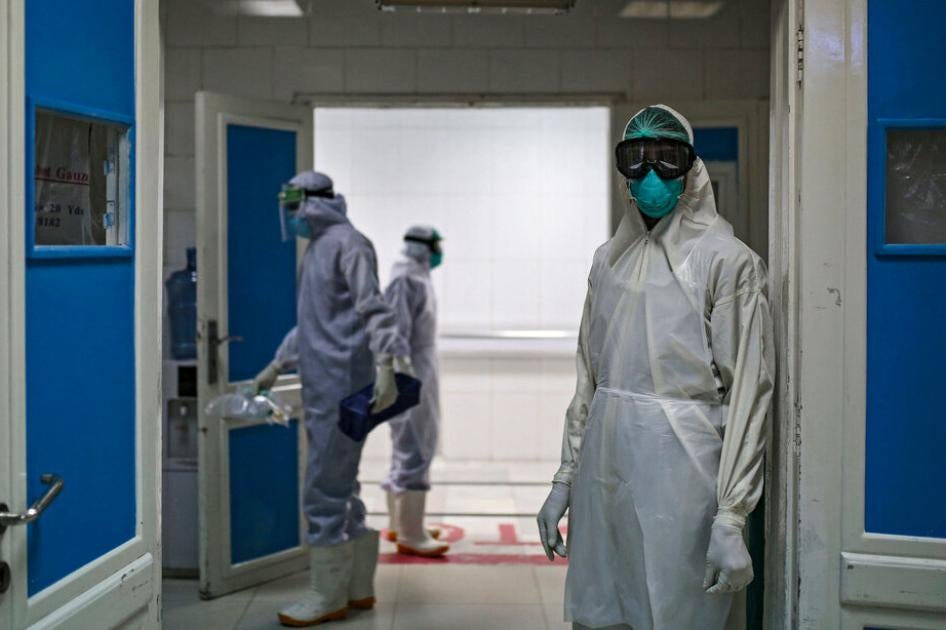 عامل صحي يرتدي زيا وقائيا كاملا يقف أمام باب وحدة الرعاية المركزة في مستشفى يُعالَج فيه مرضى فيروس "كورونا" في صنعاء، اليمن، في 15 يونيو/حزيران 2020. 