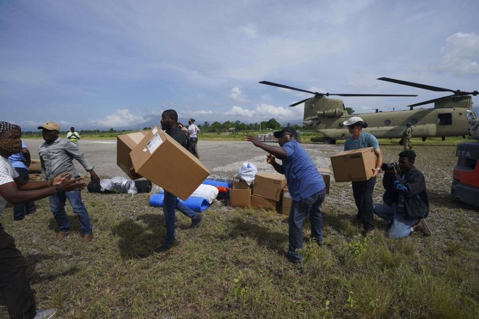 Moradores ajudam a equipe de resposta a desastres da Equipe Rubicon a descarregar suprimentos de um helicóptero do Exército dos EUA, no aeroporto, para levar ao hospital onde a equipe está tratando feridos no terremoto de magnitude 7,2 em Les Cayes, Haiti, quinta-feira, 19 de agosto de 2021. 