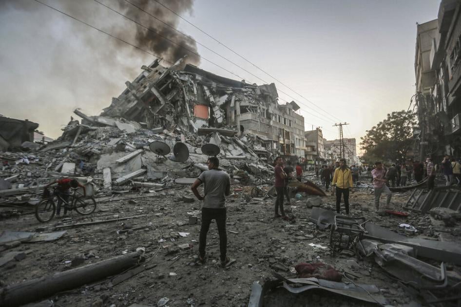 People in the Gaza Strip stand near the site of the collapsed al-Shorouk tower