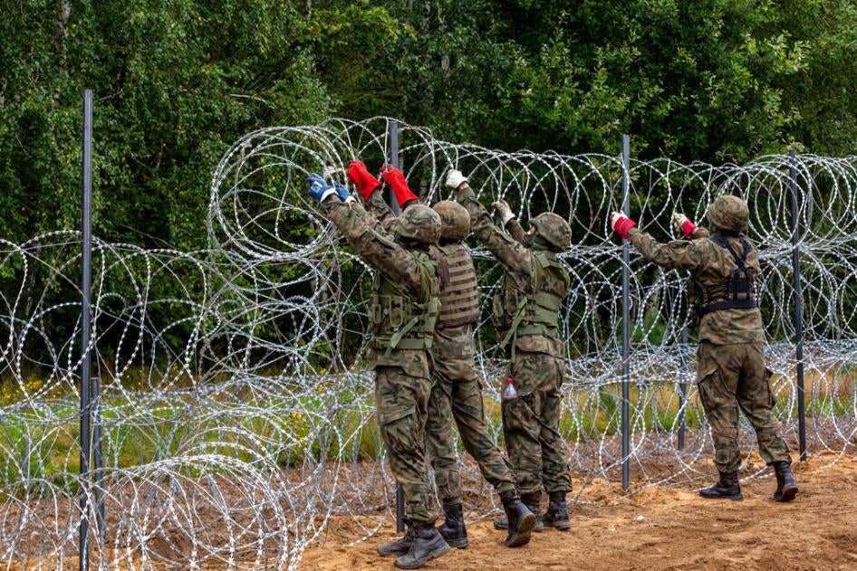 Polish soldiers build a fence with concertina wire at the border with Belarus in Krynki, Poland, on August 27, 2021.