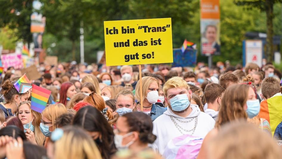 Eine demonstrierende Person auf einem Protestzug am Christopher Street Day 2021 in Oldenburg mit einem Schild mit der Aufschrift "Ich bin 'Trans' und das ist gut so!", am 21. September 2021. © 2021 Mohssen Assanimoghaddam/picture-alliance/dpa/AP Images