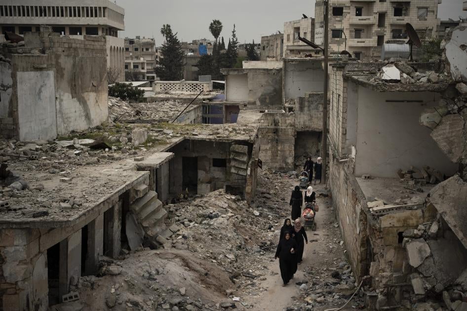 نساء يسرن في حي تضرر بشدة من الغارات الجوية في إدلب بسوريا، 12 مارس/آذار 2020. محافظة إدلب هي آخر منطقة خاضعة لسيطرة المعارضين للحكومة في سوريا.