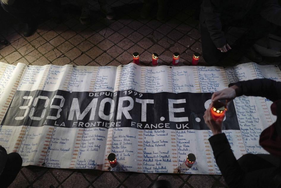 Activists and members of associations defending migrants' rights light candles in front of a banner reading "309 dead on the France UK border since 1999", during a gathering outside the port of Calais, northern France, November 25, 2021. 