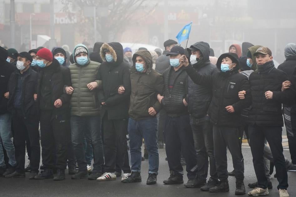 示威民眾在警察封鎖線前手挽手結成人牆，哈薩克斯坦阿拉木圖，2022年1月5日。