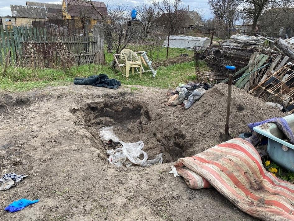 The temporary grave that Valerii Savchenko dug in his Hostomel garden to bury Liubov and Volodymyr Maksymenko. They were killed on February 28, 2022 when Russian forces opened fire on the cars in which they trying to evacuate. 