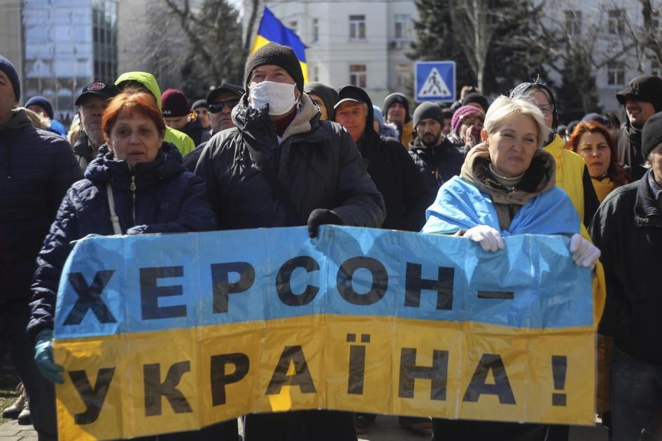 People hold a Ukrainian flag with a sign that reads: "Kherson is Ukraine", during a rally against the Russian occupation in Kherson, Ukraine, Sunday, March 20, 2022. © 2022 Olexandr Chornyi/AP