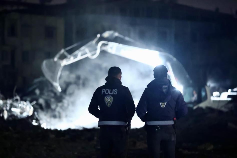 Deux policiers observaient le déblaiement de décombres de bâtiments qui s’étaient effondrés lors des tremblements de terre du 6 février, à Hatay, en Turquie, le 23 mars 2023. 
