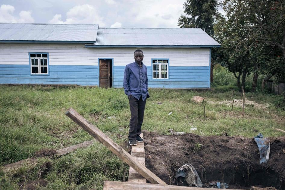 A man stands outside of a school next to a hole in the ground used as a detention place by M23 fighters in Kishishe, North Kivu, Democratic Republic of Congo, April 5, 2023.