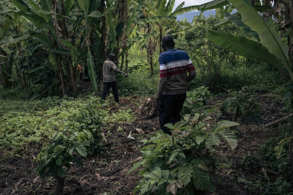 Two men indicate the position of a mass grave among banana trees near the Adventist Church on April 5, 2023. Several people were executed outside the church by M23 in November 2022 in Kishishe, eastern Democratic Republic of Congo.