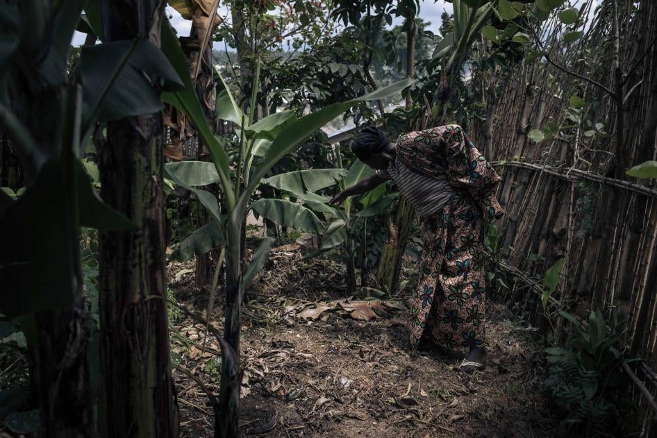A woman indicates the position of a mass grave among banana trees where about five men and boys were allegedly executed by the M23 in November 2022 in Kishishe, eastern Democratic Republic of Congo.