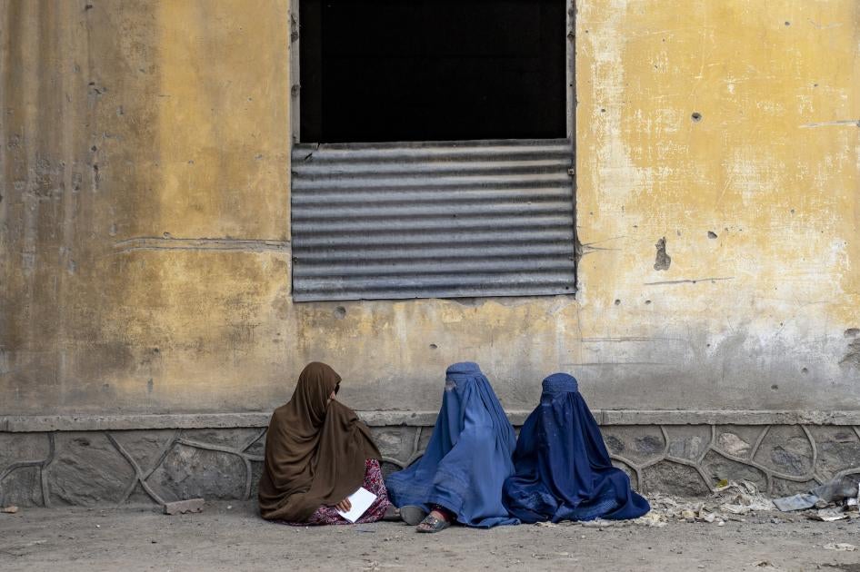 Trois femmes afghanes assises devant un immeuble à Kaboul, en Afghanistan, attendaient la distribution de rations alimentaires par un groupe d'aide humanitaire, le 23 mai 2023. 